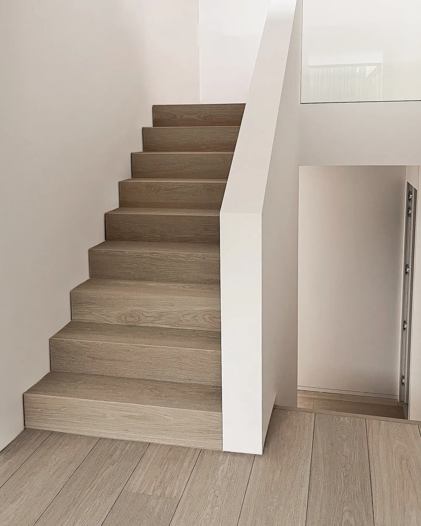 Dubbele houten trap met eiken treden in een witte trappenhal